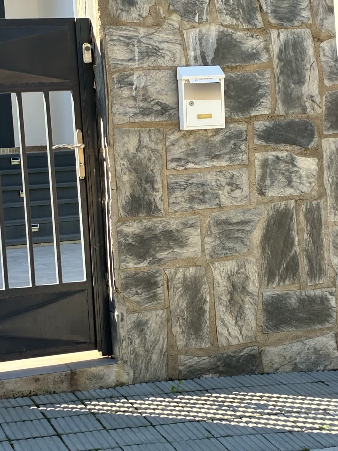 Buzón blanco en un muro de piedra de Vidreres con el flyer recién metido
