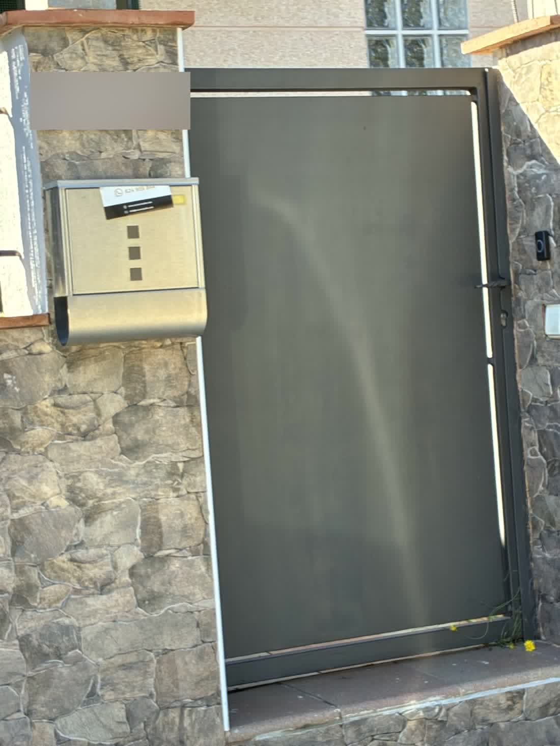 Buzón de acero en el pilar de una casa de Vidreres con el flyer asomando