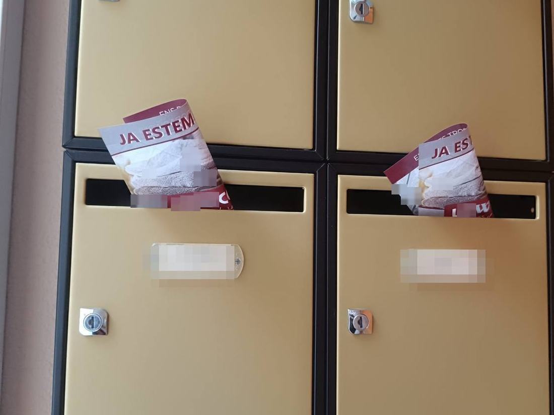 Buzones beige de una finca de Mataró con el flyer «Ja estem oberts» asomando