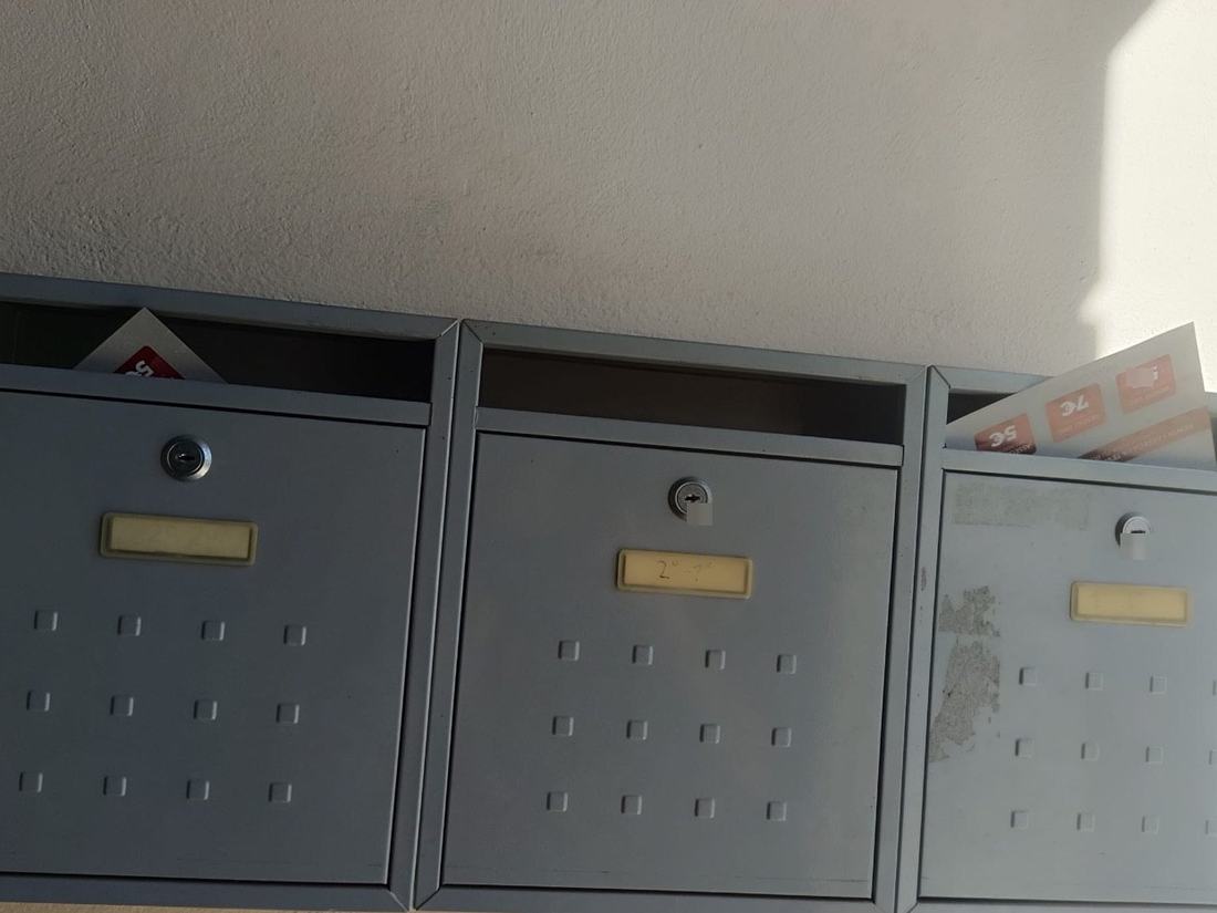 Buzones grises de un portal de Mataró con el flyer del cliente ya repartido